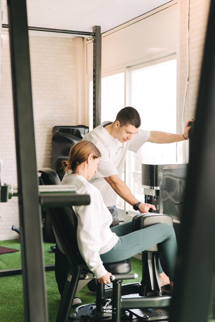 Personal trainer guiding a client on a gym machine