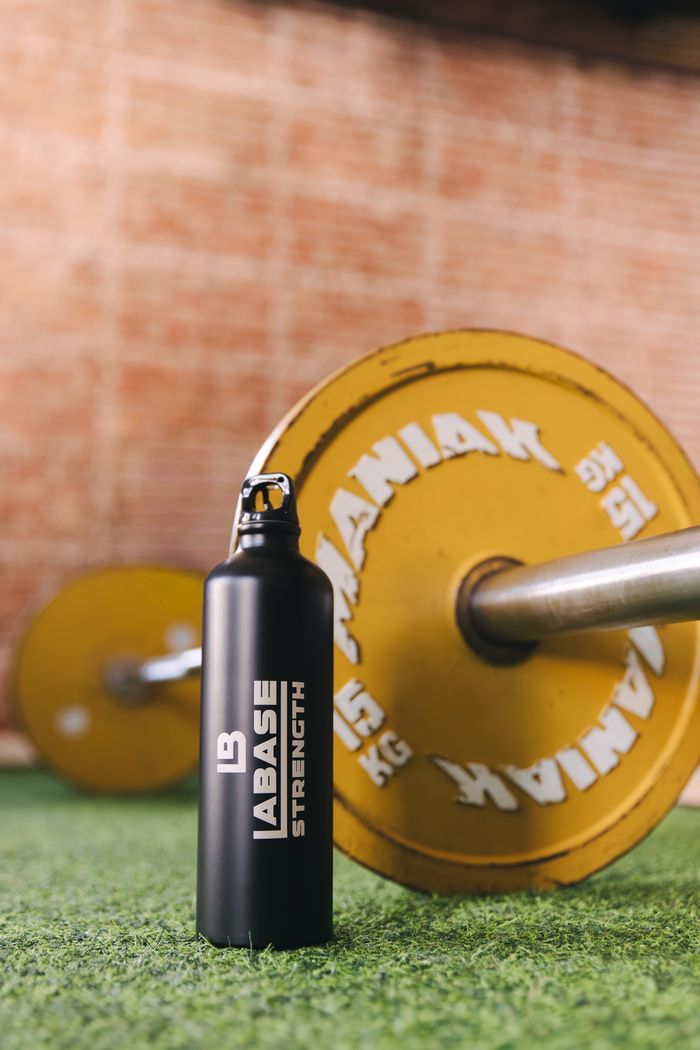 Water bottle and yellow weight plate on gym turf